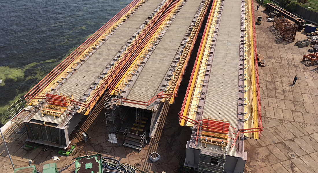Glass reinforced polymer permanent formwork installed on large steel bridge beams, showing shear connectors and white GRP panels used in infrastructure construction.