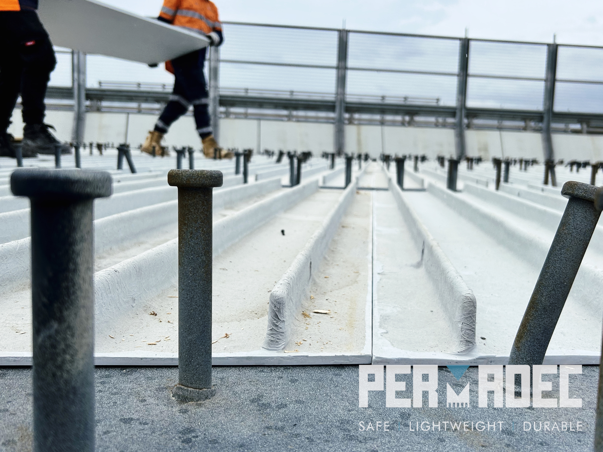 Close-up of Permadec GRP formwork panels installed between shear studs on a bridge deck, with workers using the panels as a safe working platform – glass reinforced polymer permanent formwork system.
